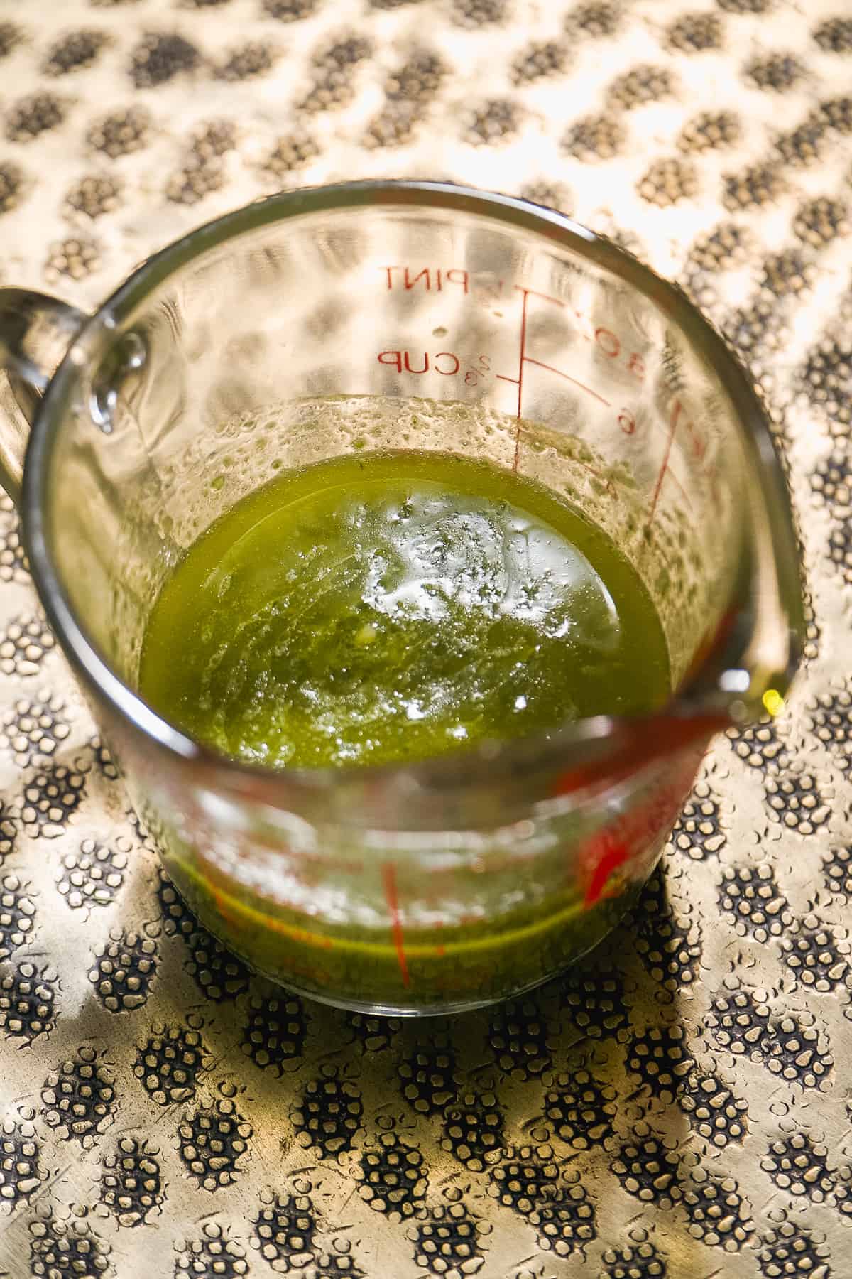 Basil pesto in a glass measuring cup.