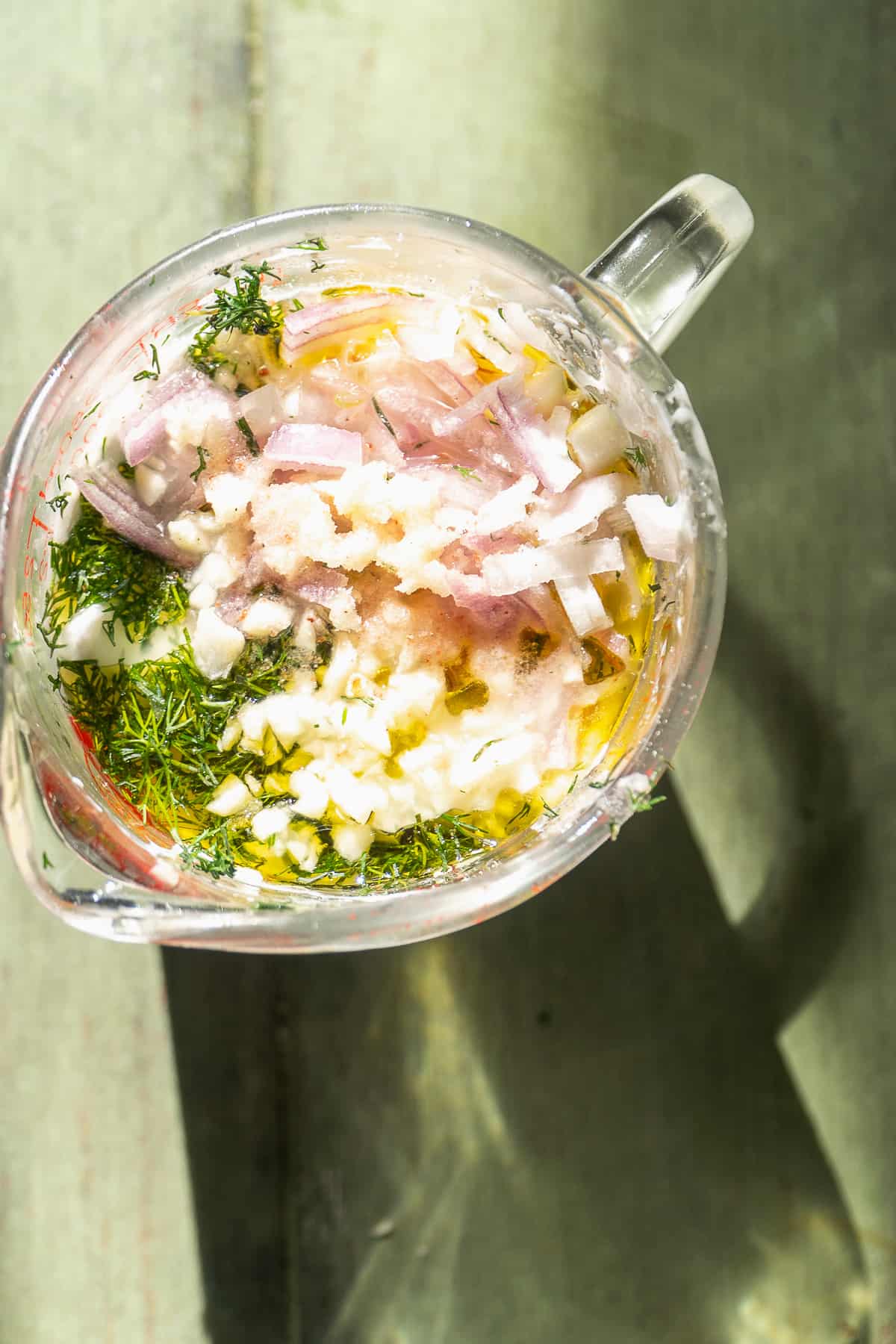 Dill greek yogurt dressing in a measuring cup about to be mixed.