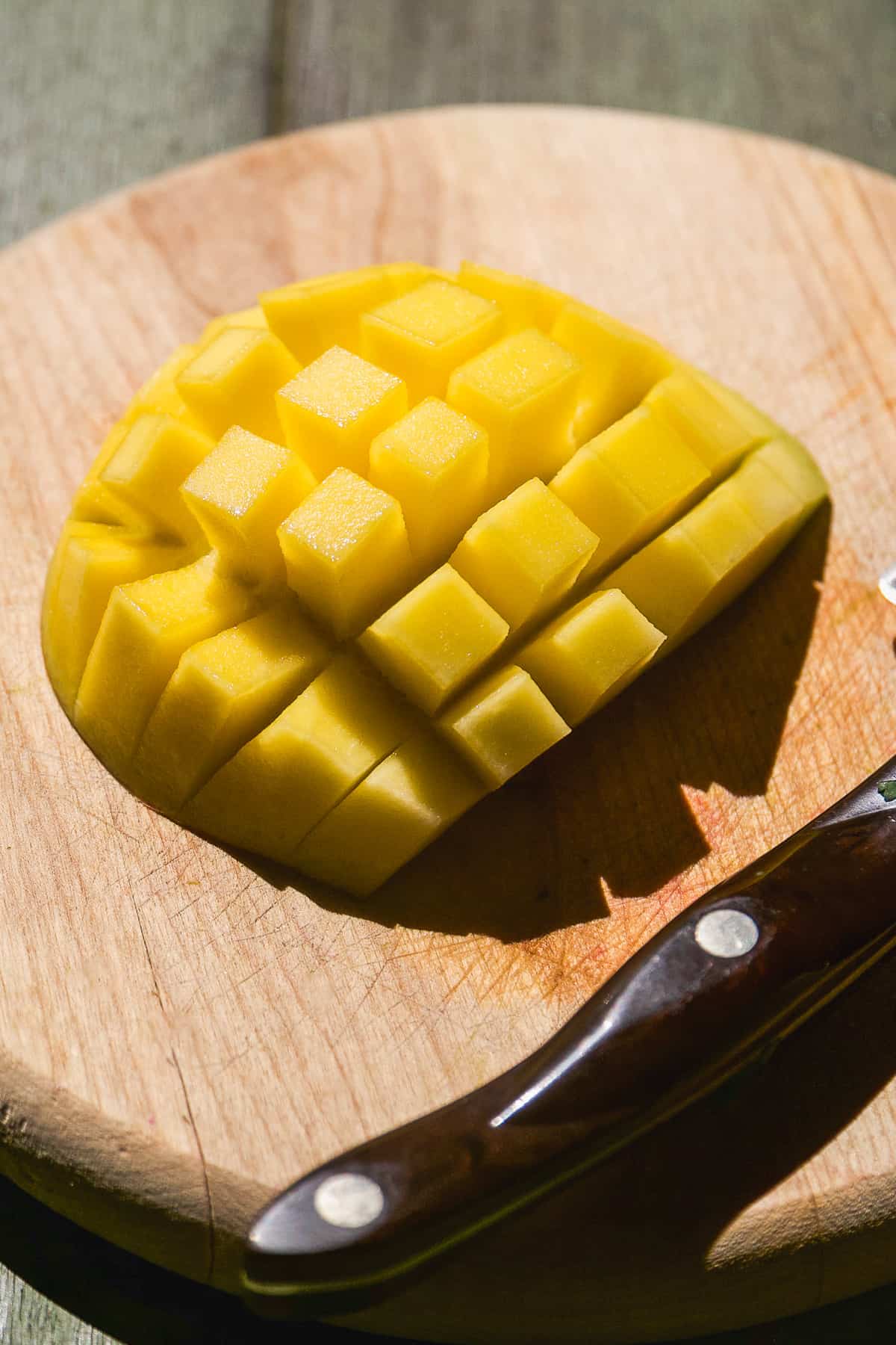 Mango cut into cubes on a wooden cutting board.