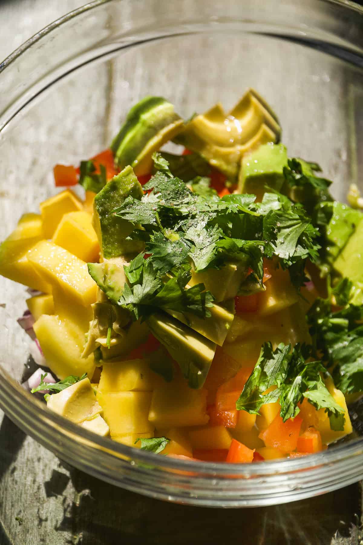 Mango avocado salsa with cilantro about to be mixed in a bowl.