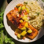 Plate with a salmon filet and mango avocado salsa and quinoa.