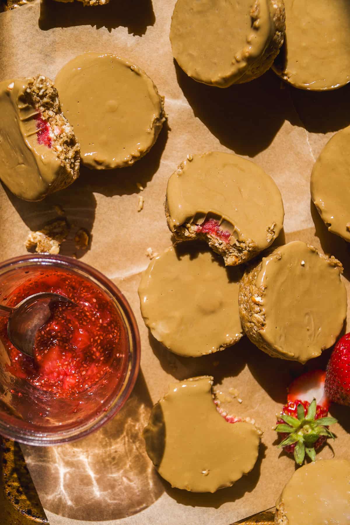 Strawberry jam filled oat cups on a cookie sheet.