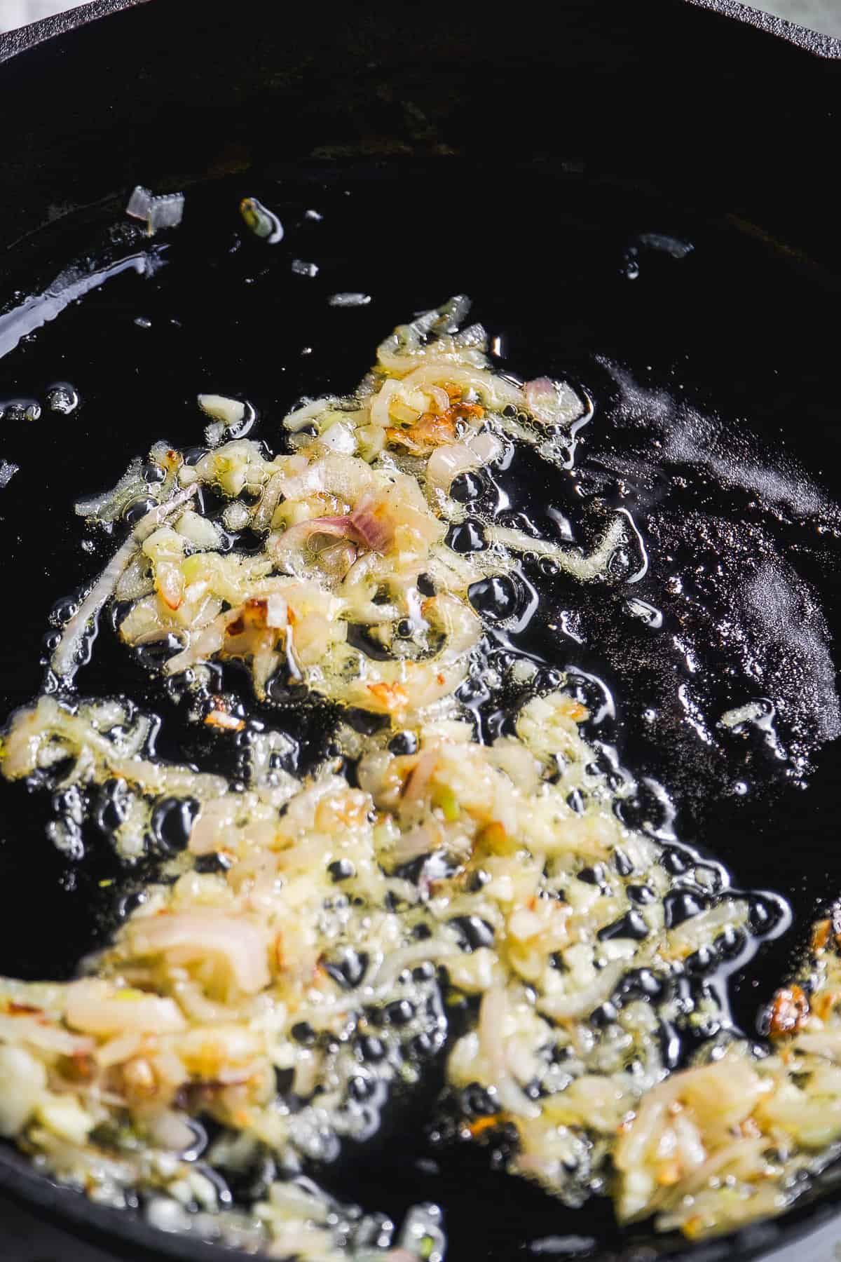 Onions cooking in olive oil in a skillet.