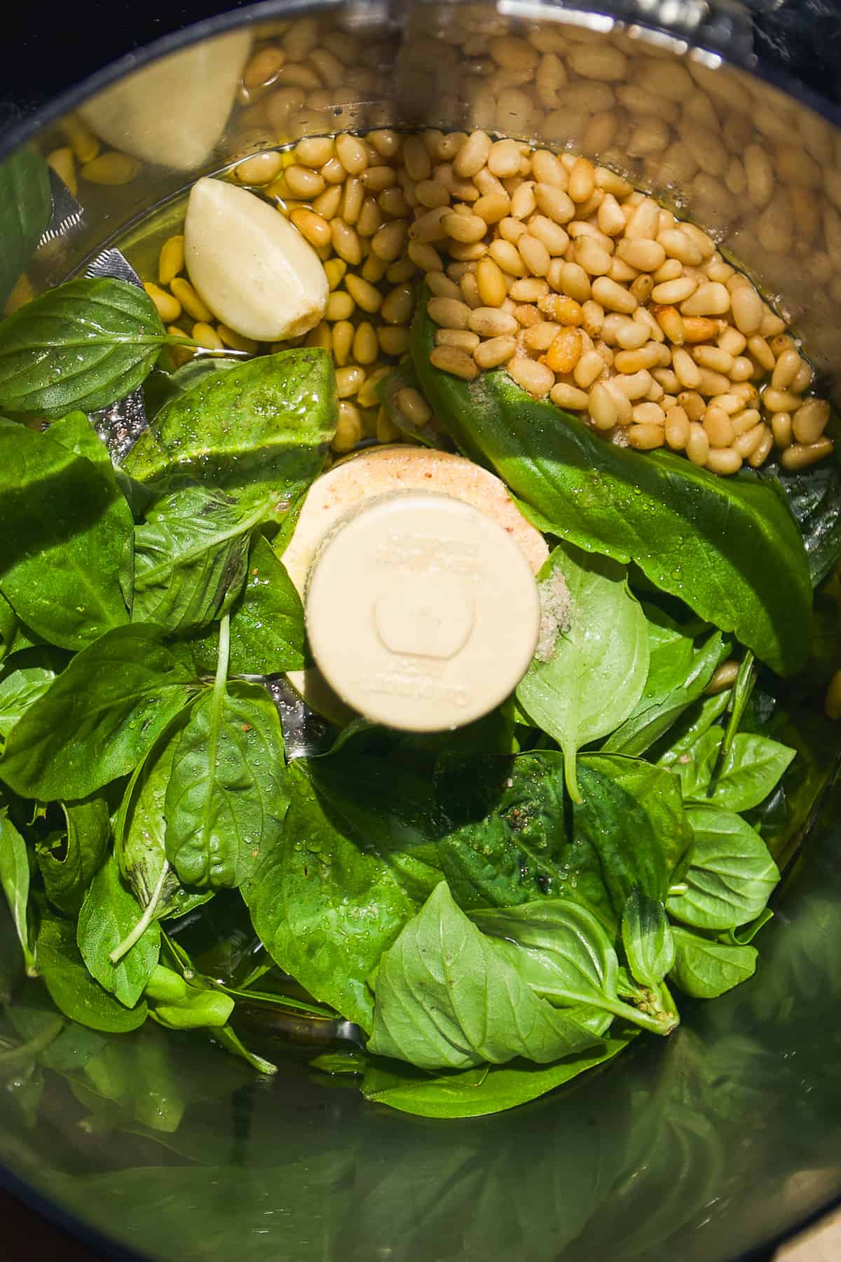Basil pesto ingredients in a food processor about to be mixed.