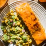Peach glazed salmon on a plate with an avocado green salad.
