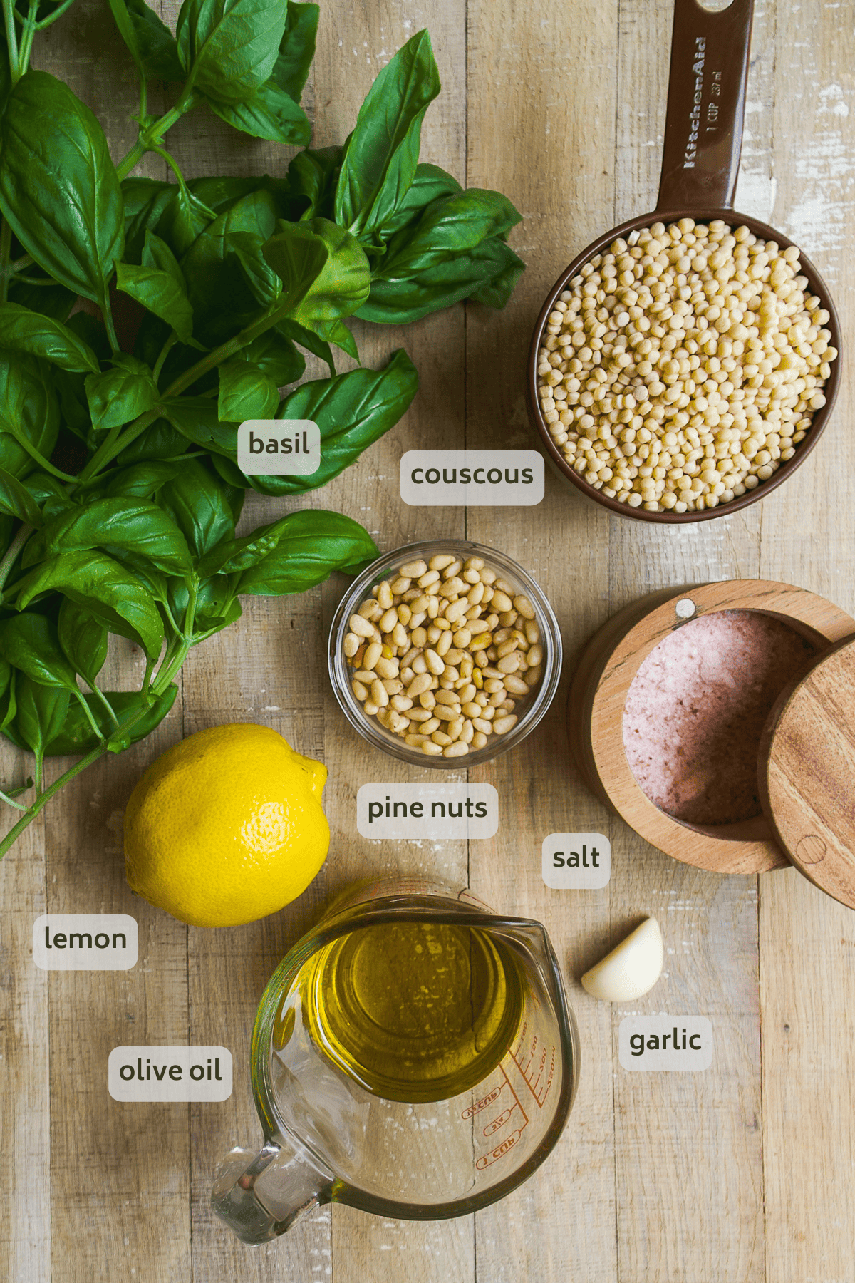 Pesto couscous ingredients on a wooden surface.