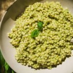Pesto couscous in a bowl with basil.