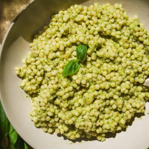 Pesto couscous in a bowl with basil.