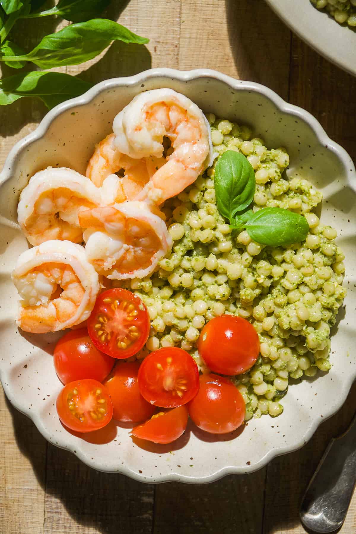 Pesto shrimp bowls with tomatoes and basil leaves.