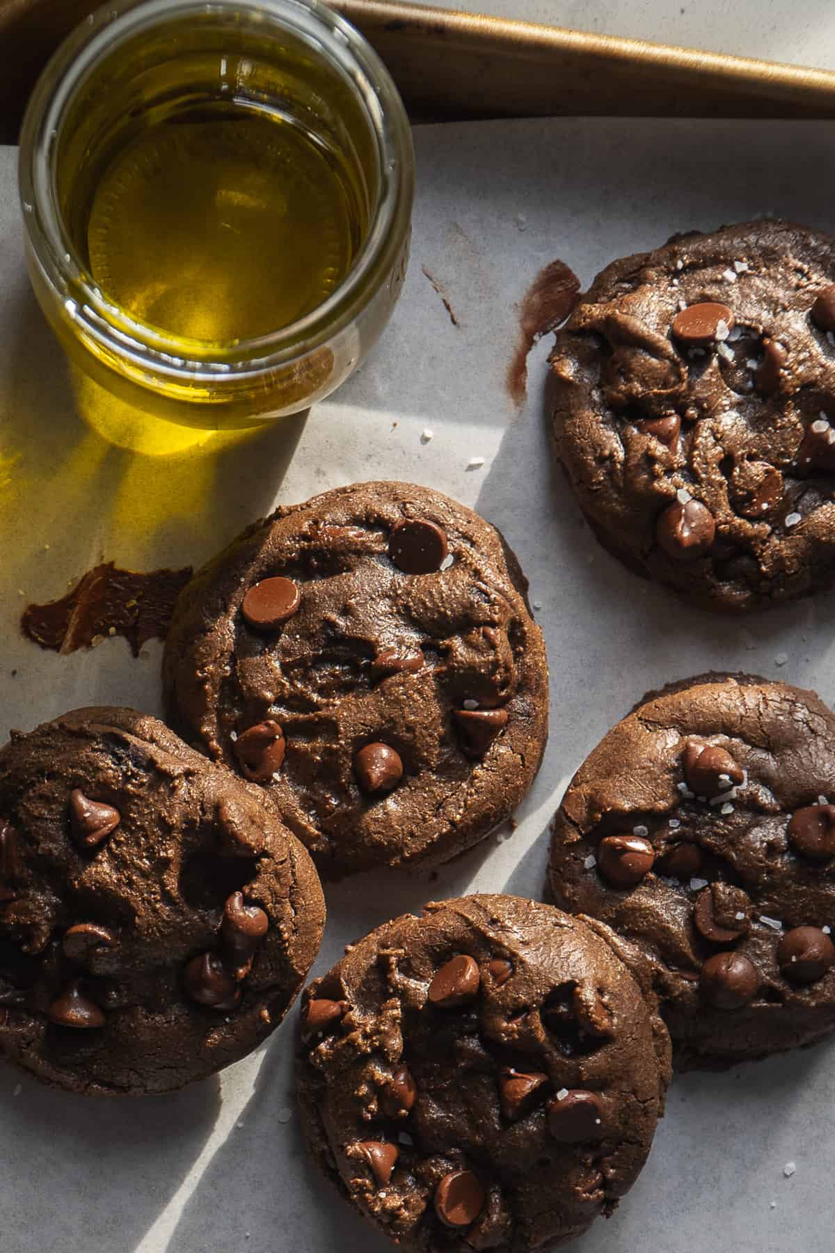 Chocolate olive oil cookies with chocolate chips on a baking sheet.