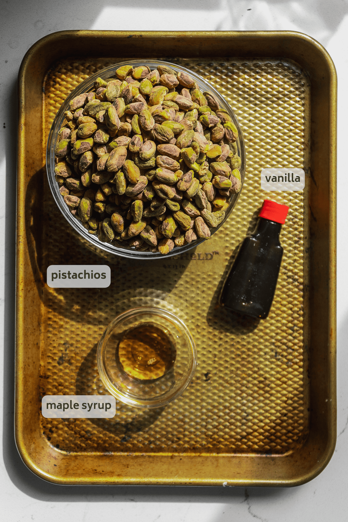Pistachio butter ingredients on a gold baking sheet.