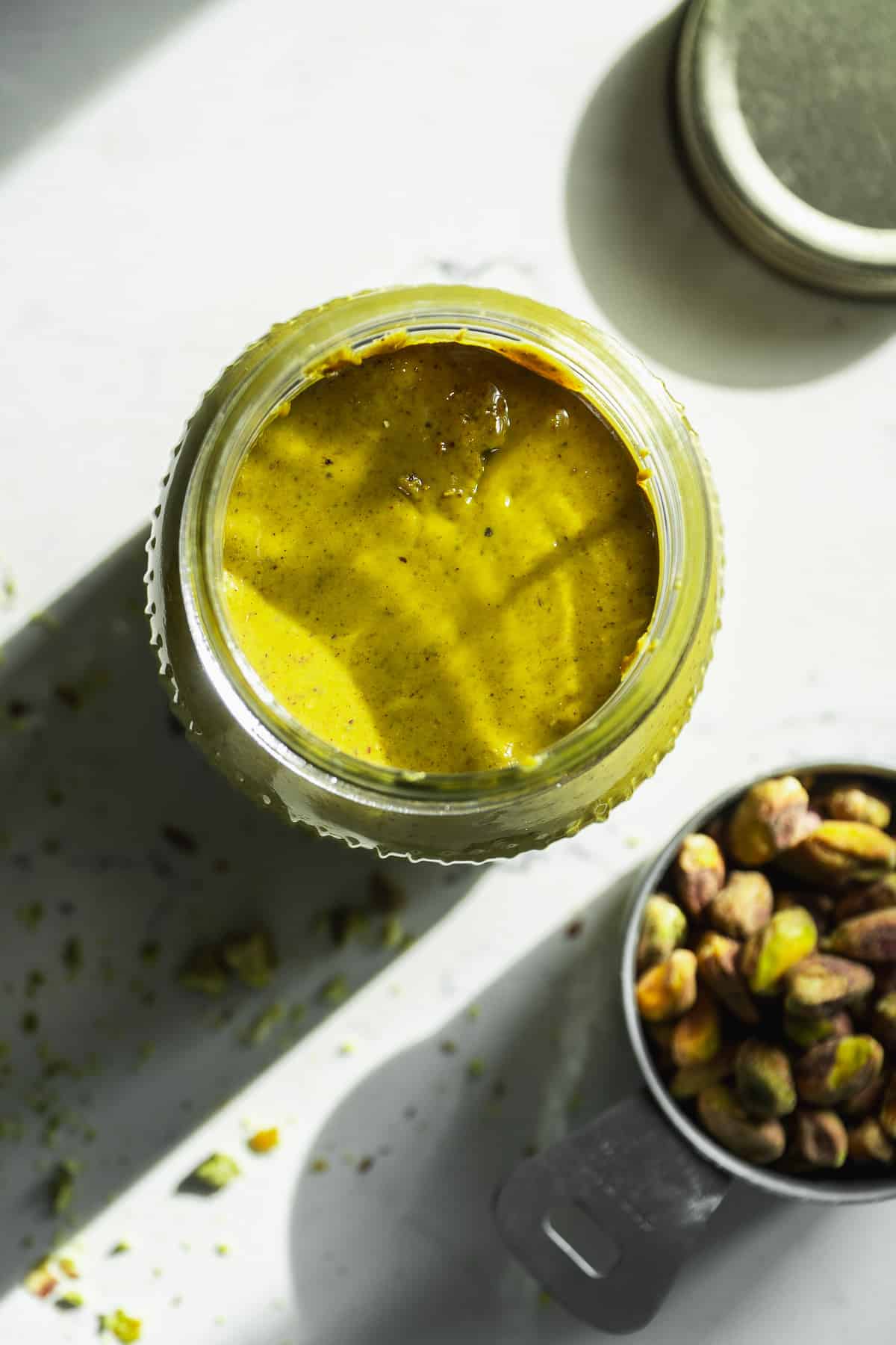 Jar of pistachio butter from above with the lid off.