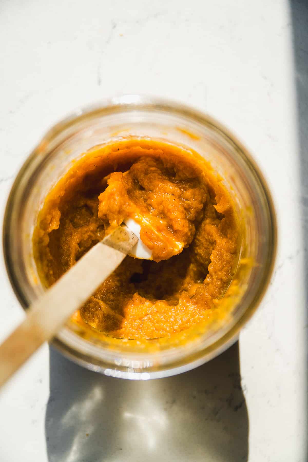 Pumpkin puree mixed in a mason jar with a spatula.