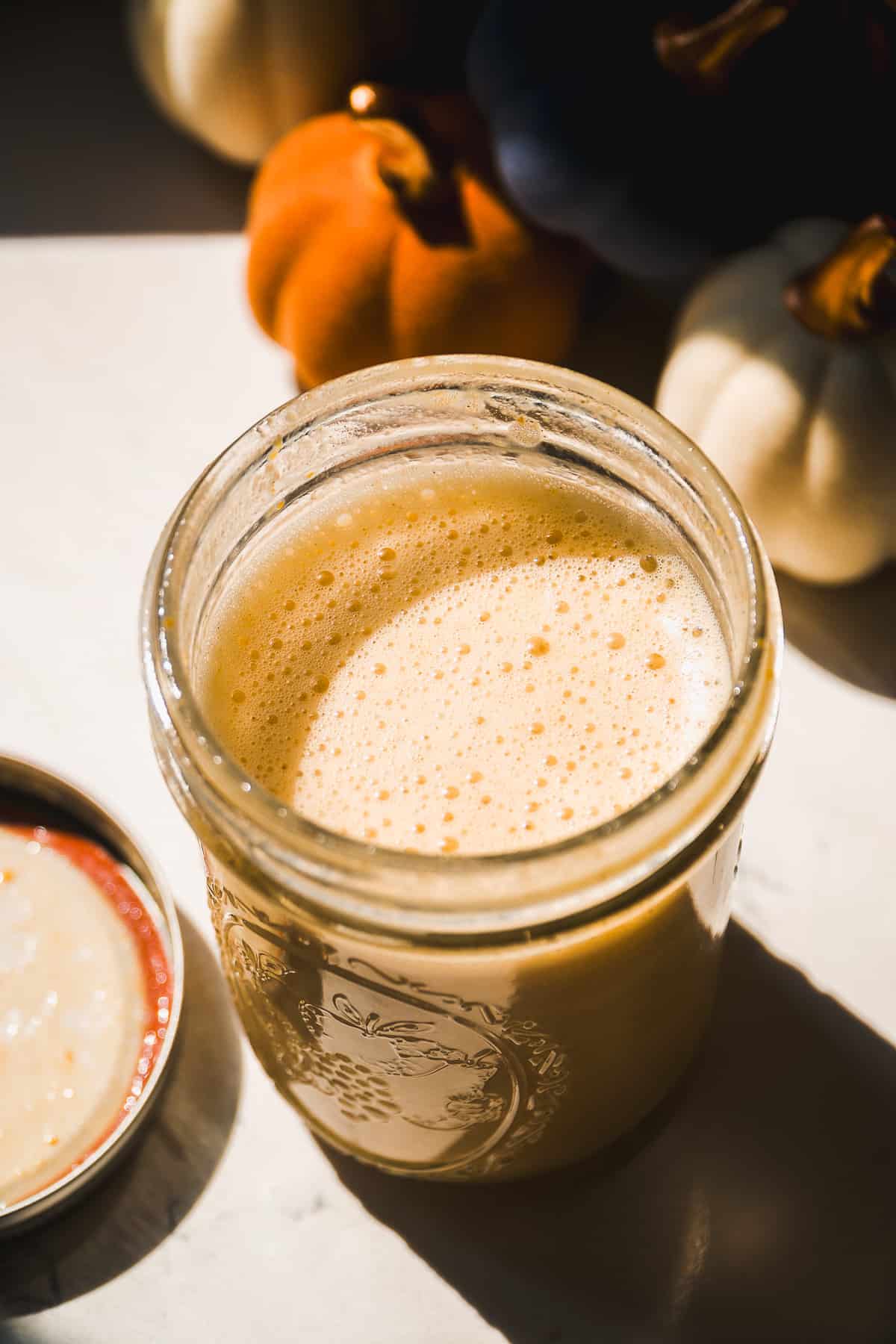 Pumpkin cream cold foam in a mason jar with bubbles on top.