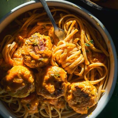 Pumpkin pasta sauce with noodles and meatballs in a dish.