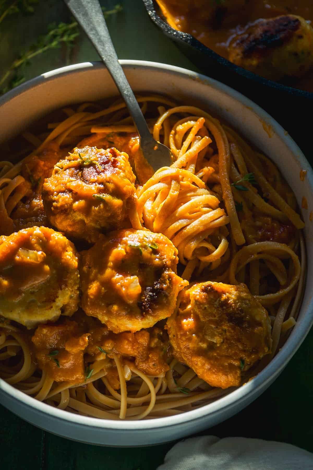 Tomato pumpkin pasta sauce with noodles and meatballs in a dish.