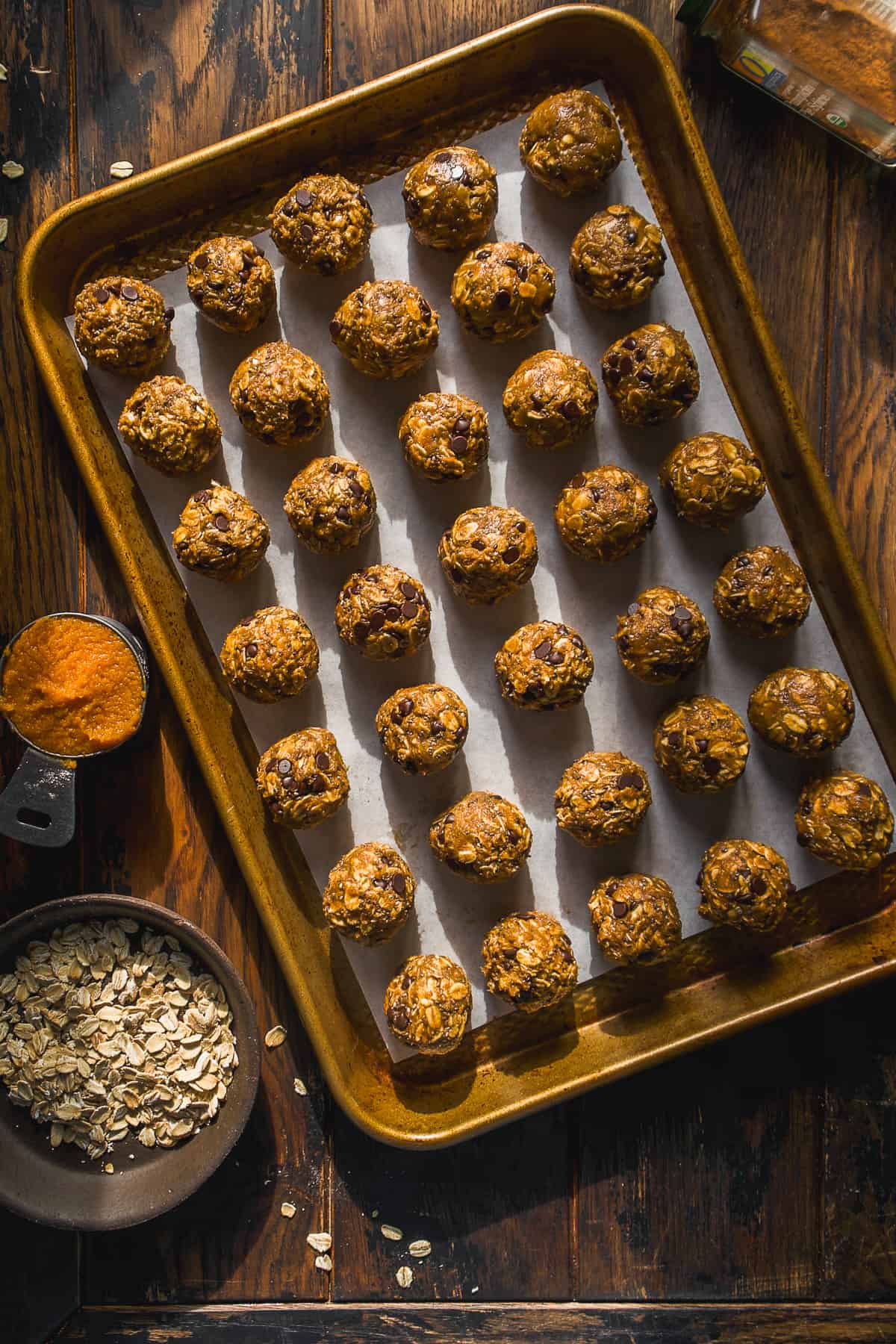 Pumpkin energy bites lined up on a baking sheet.