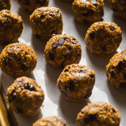 Pumpkin protein balls on parchment paper in a line.