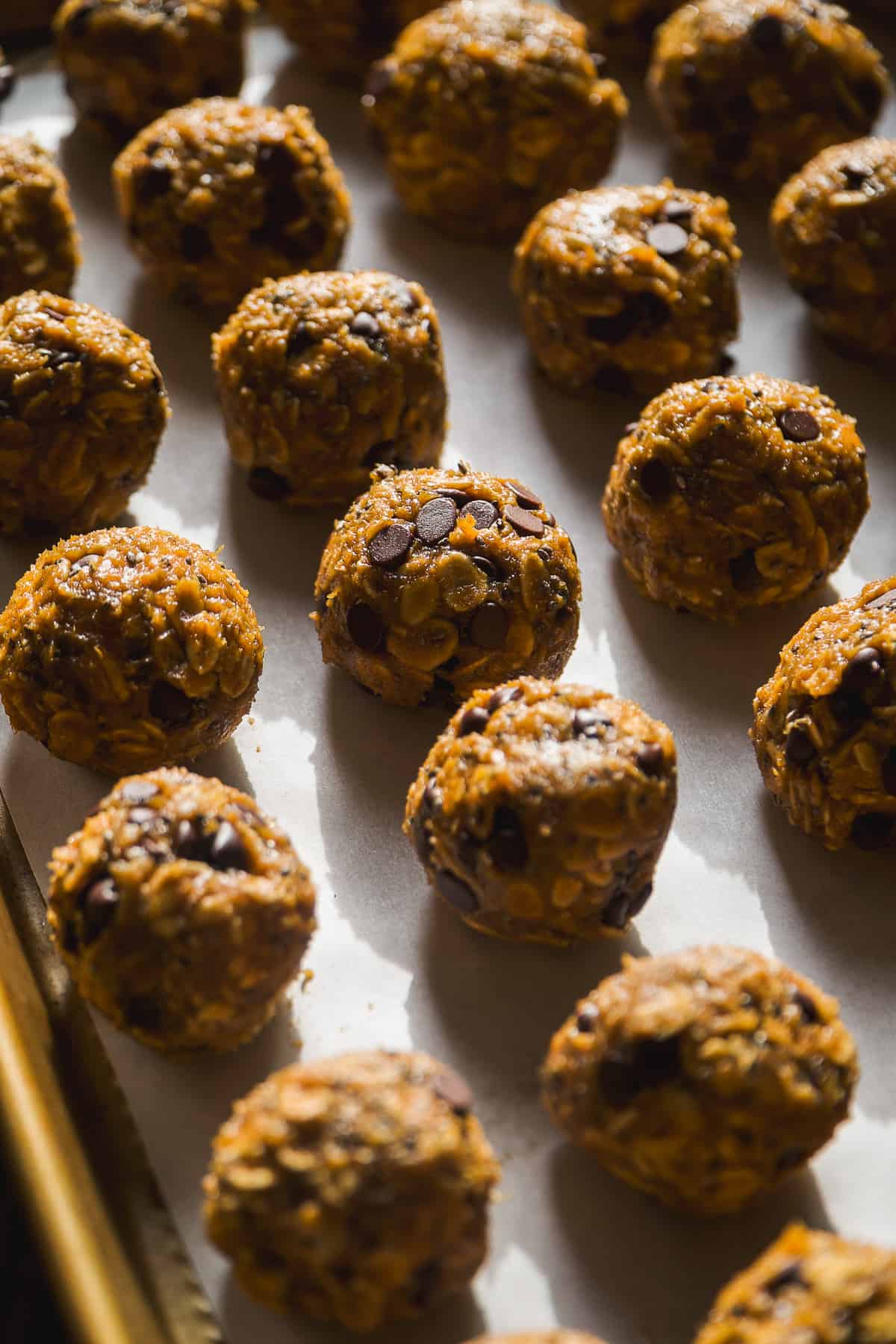 Pumpkin protein balls on parchment paper in a line.