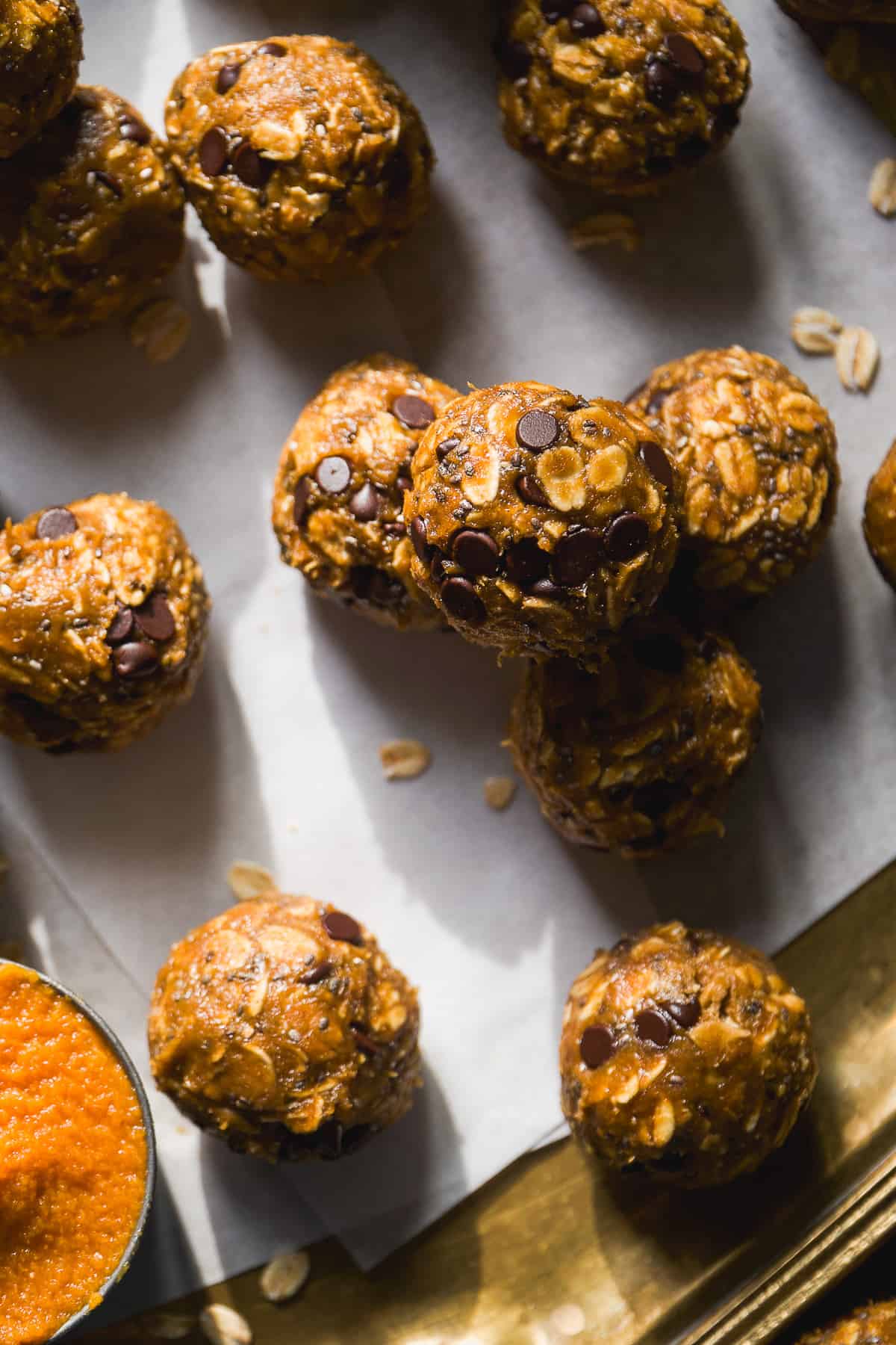 Pumpkin protein balls with chocolate chips on a gold platter.