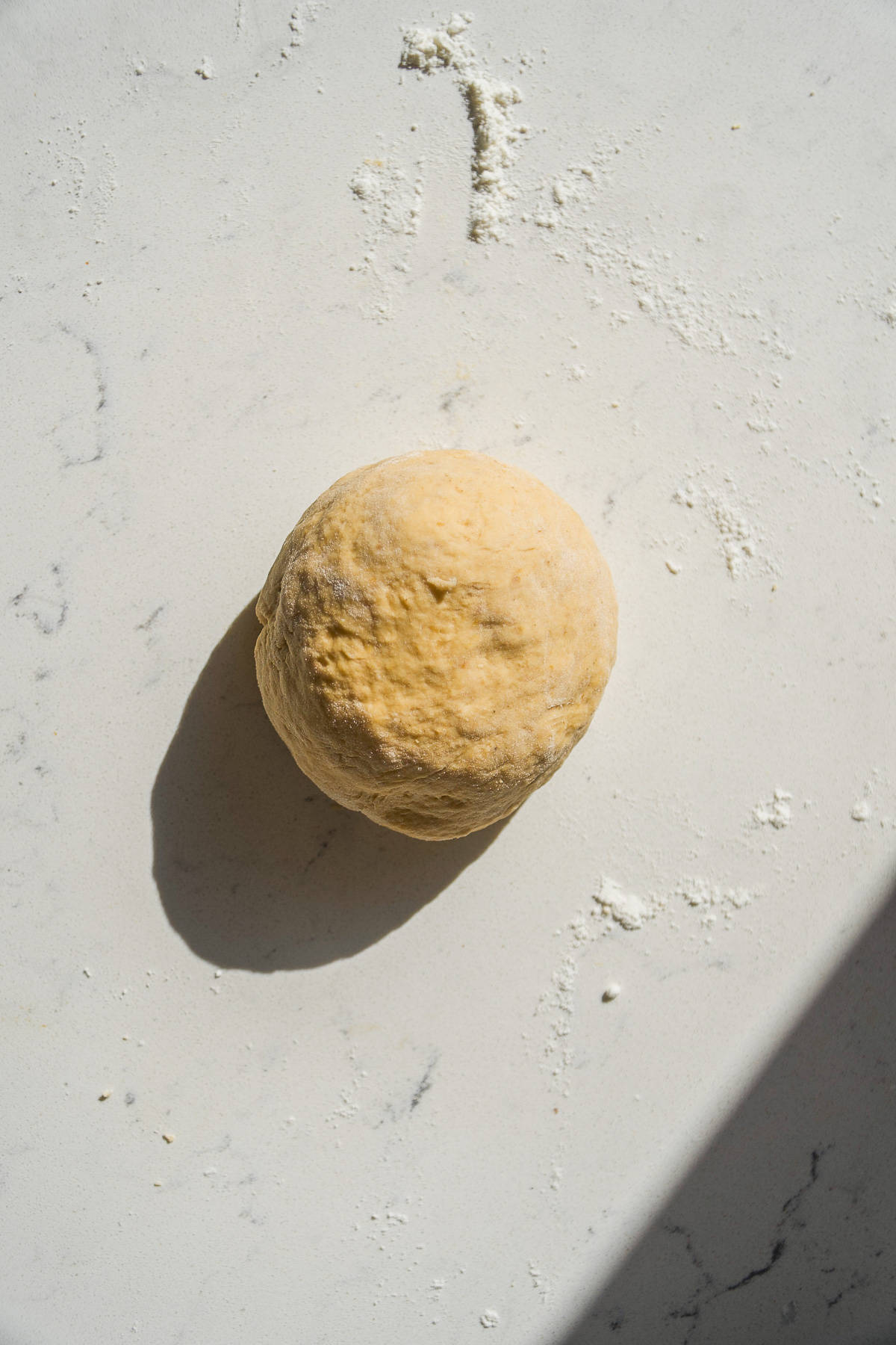 Pumpkin spice cinnamon roll dough in a round ball on a floured surface.