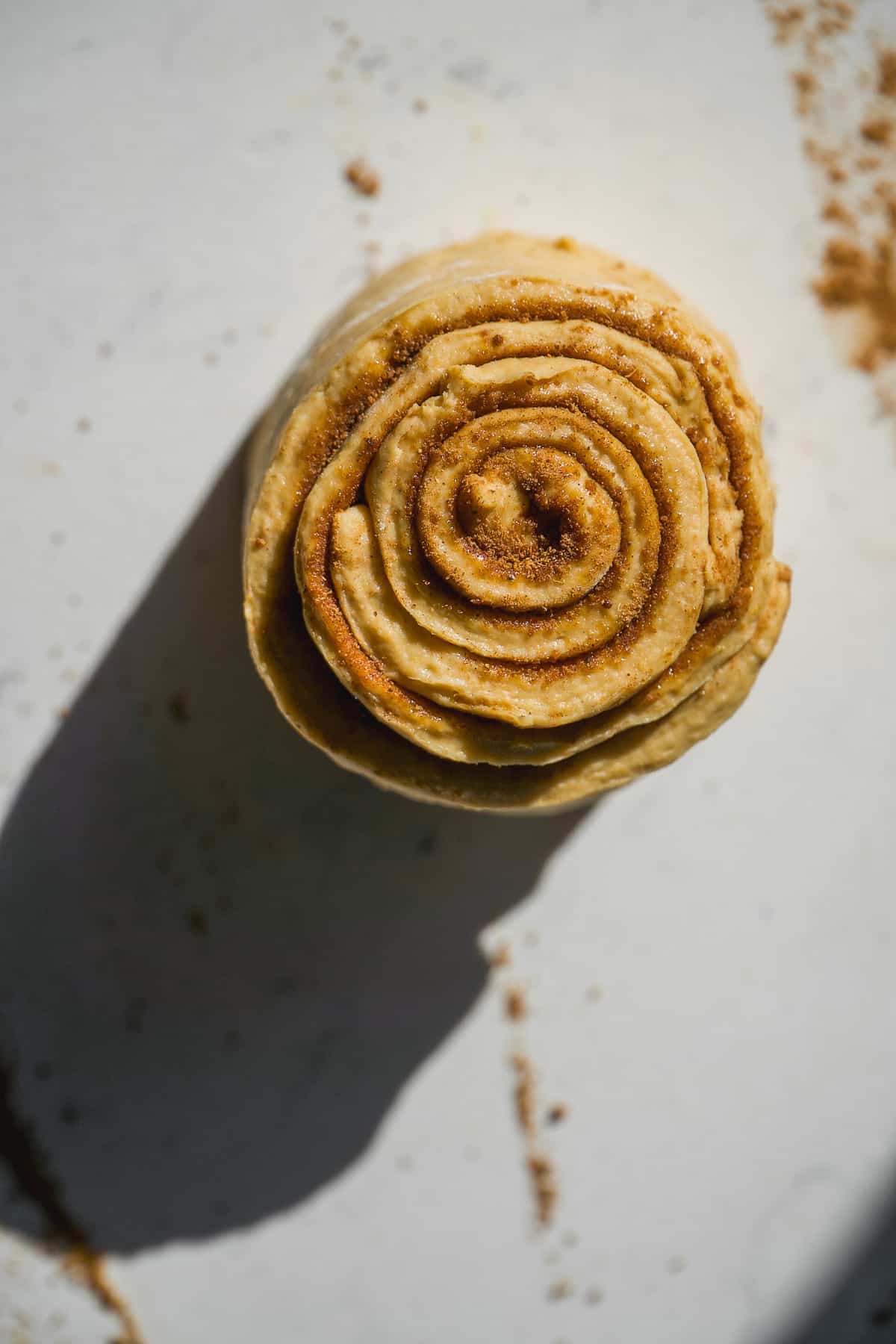 Pumpkin spice cinnamon roll rolled up on a marble surface.