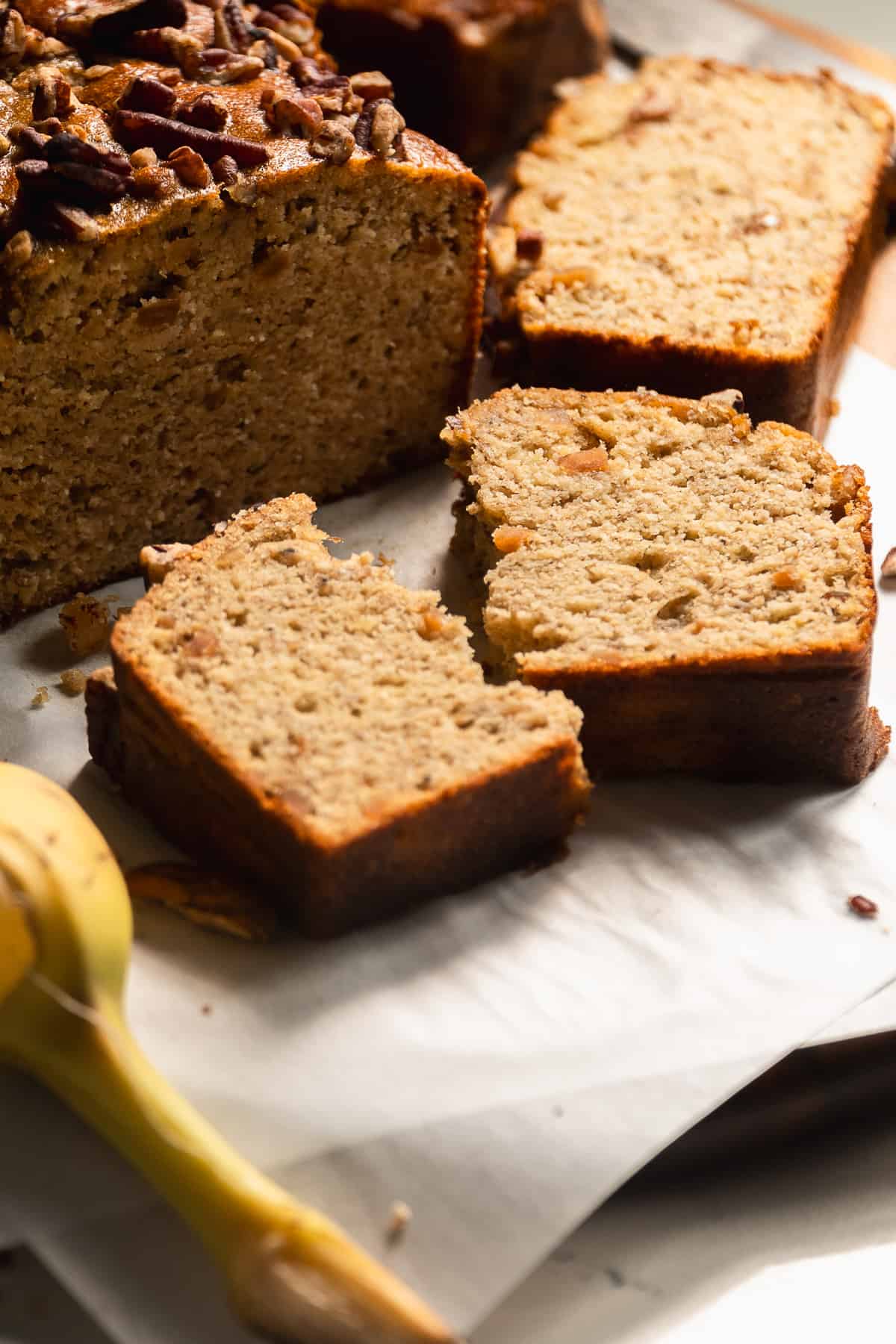 A slice of sugar free banana bread laying flat on a piece of parchment paper.