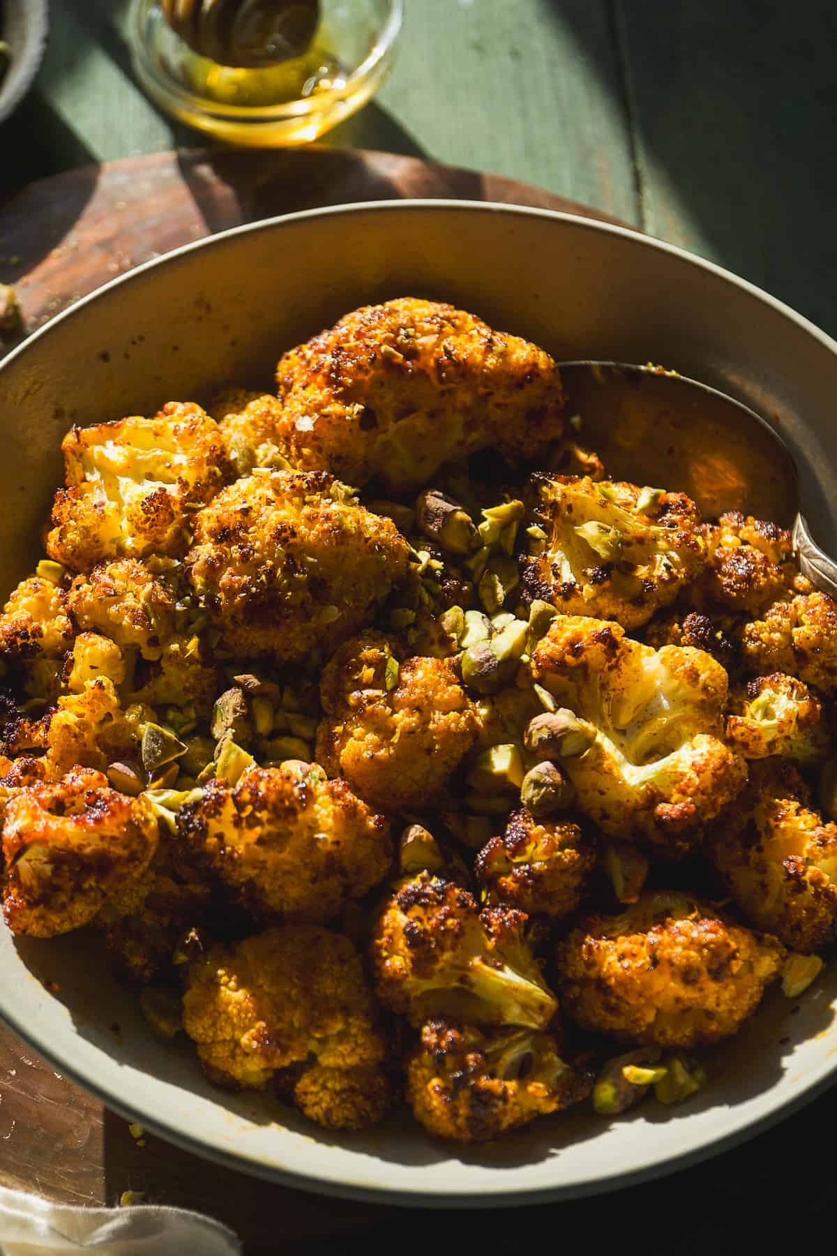 Bowl of air fry cauliflower florets seasoned with honey and pistachios.