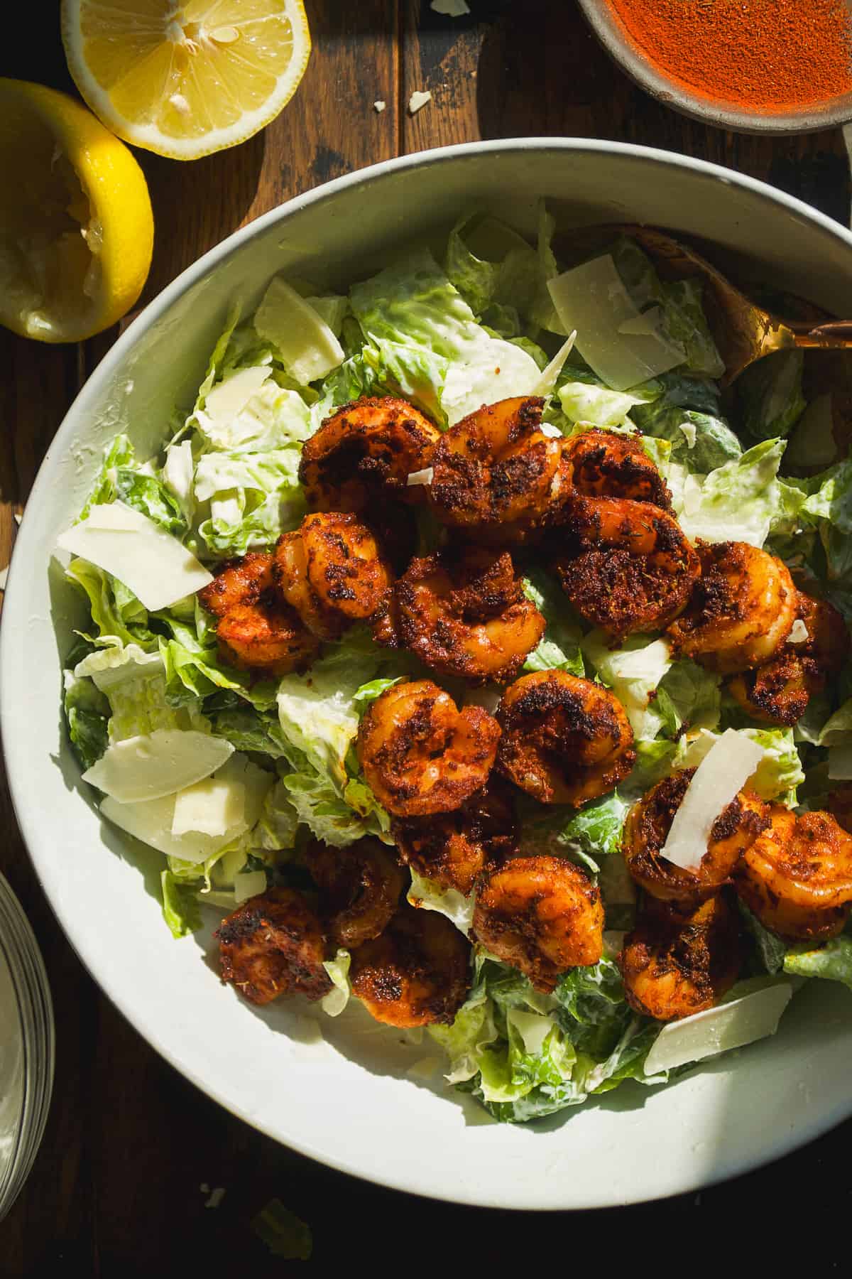 A large bowl with caesar salad and blackened shrimp on top.