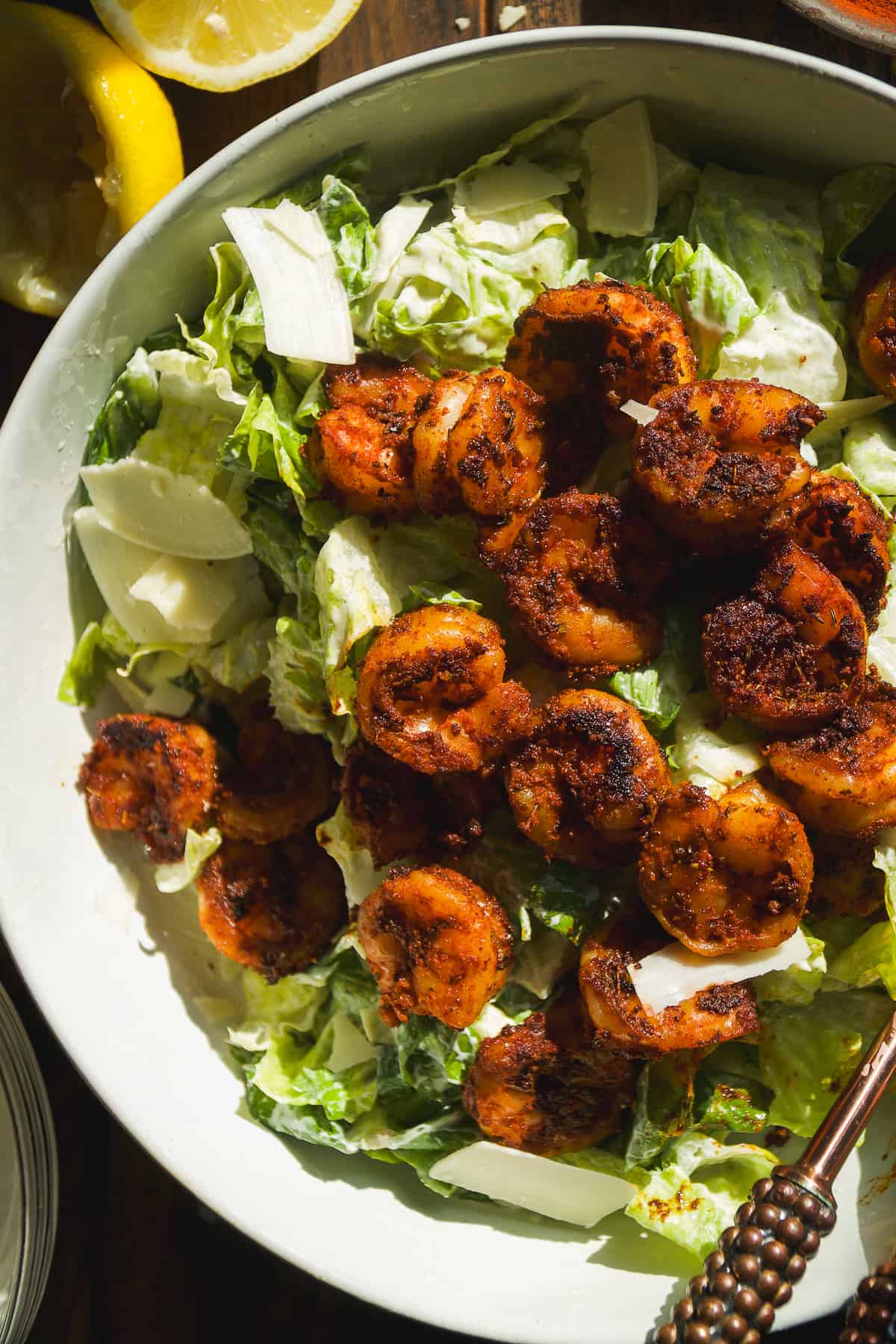 Caesar salad with blackened shrimp on top in a large bowl.