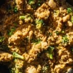 Cheesy chicken and rice casserole in a cast iron skillet with broccoli.