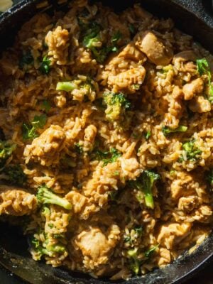 Cheesy chicken and rice casserole in a cast iron skillet with broccoli.