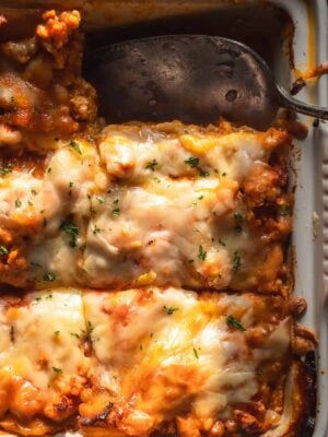 Gluten free lasagna in a baking dish with cheese on top.