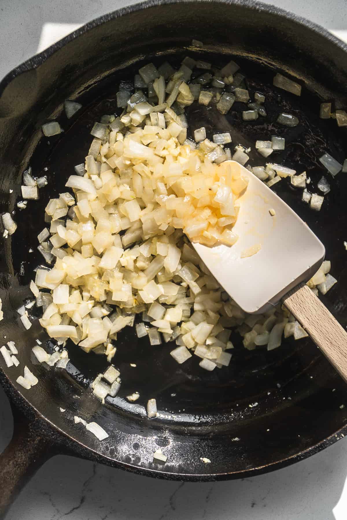 White onions cooking in a cast iron skillet.