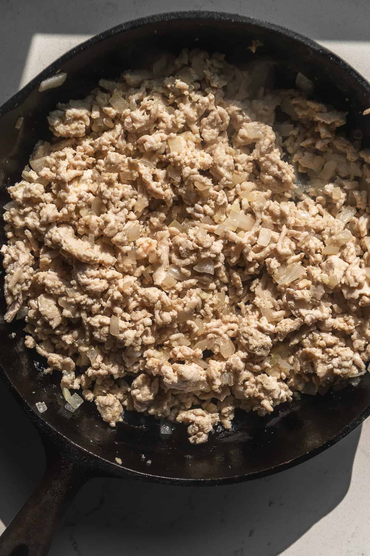 Ground turkey cooking in a cast iron skillet.