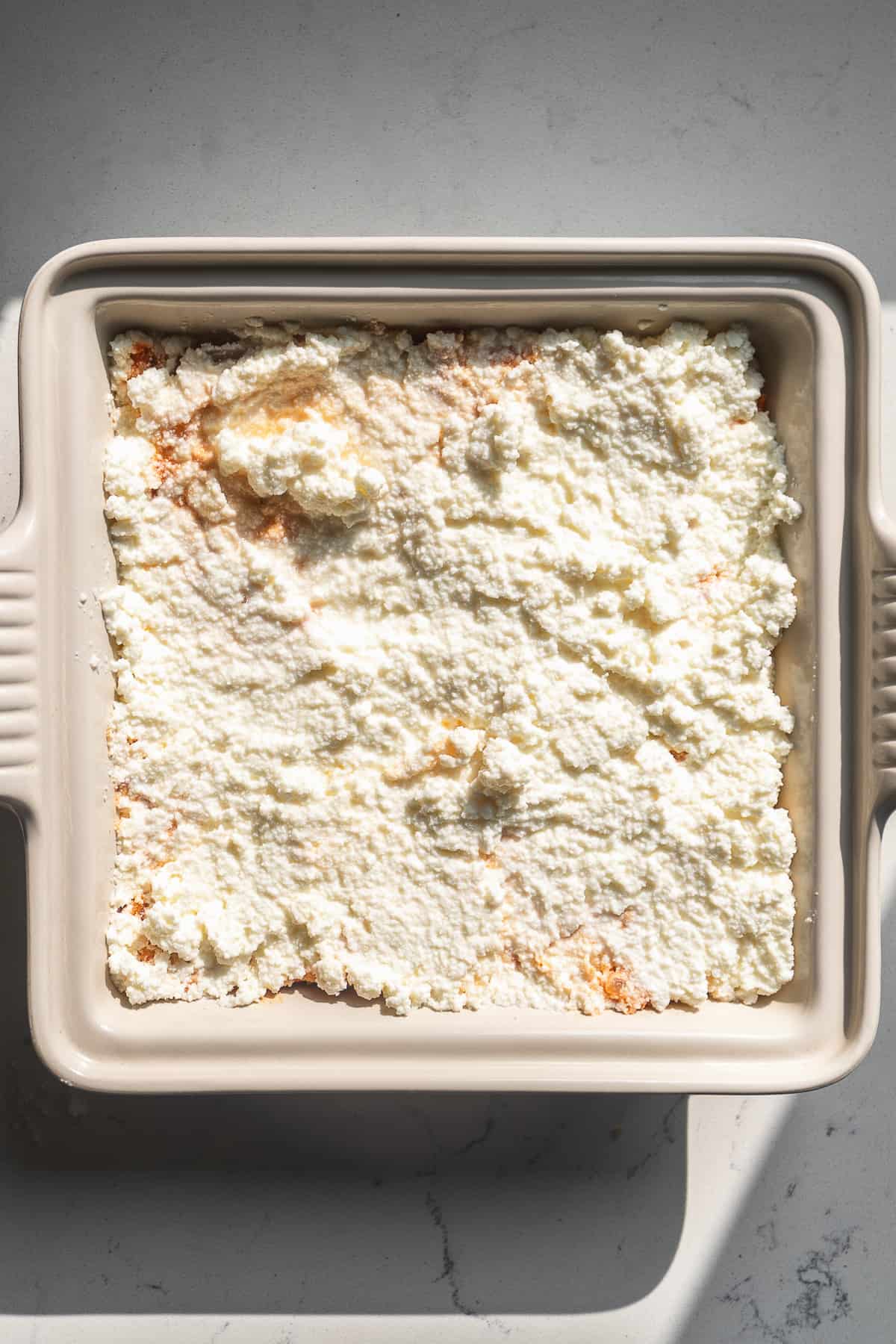 Ricotta cheese spread into a layer on top of ground turkey.