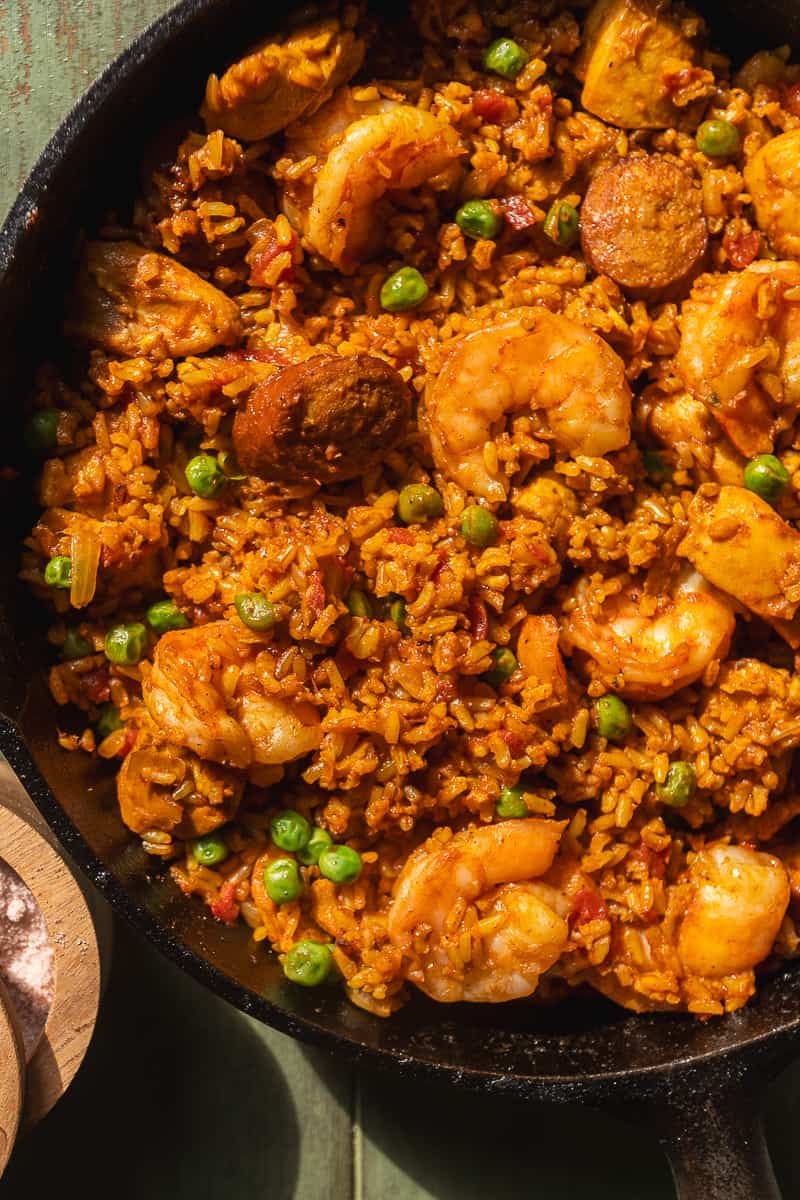 Shrimp and chorizo paella in a skillet with peas.