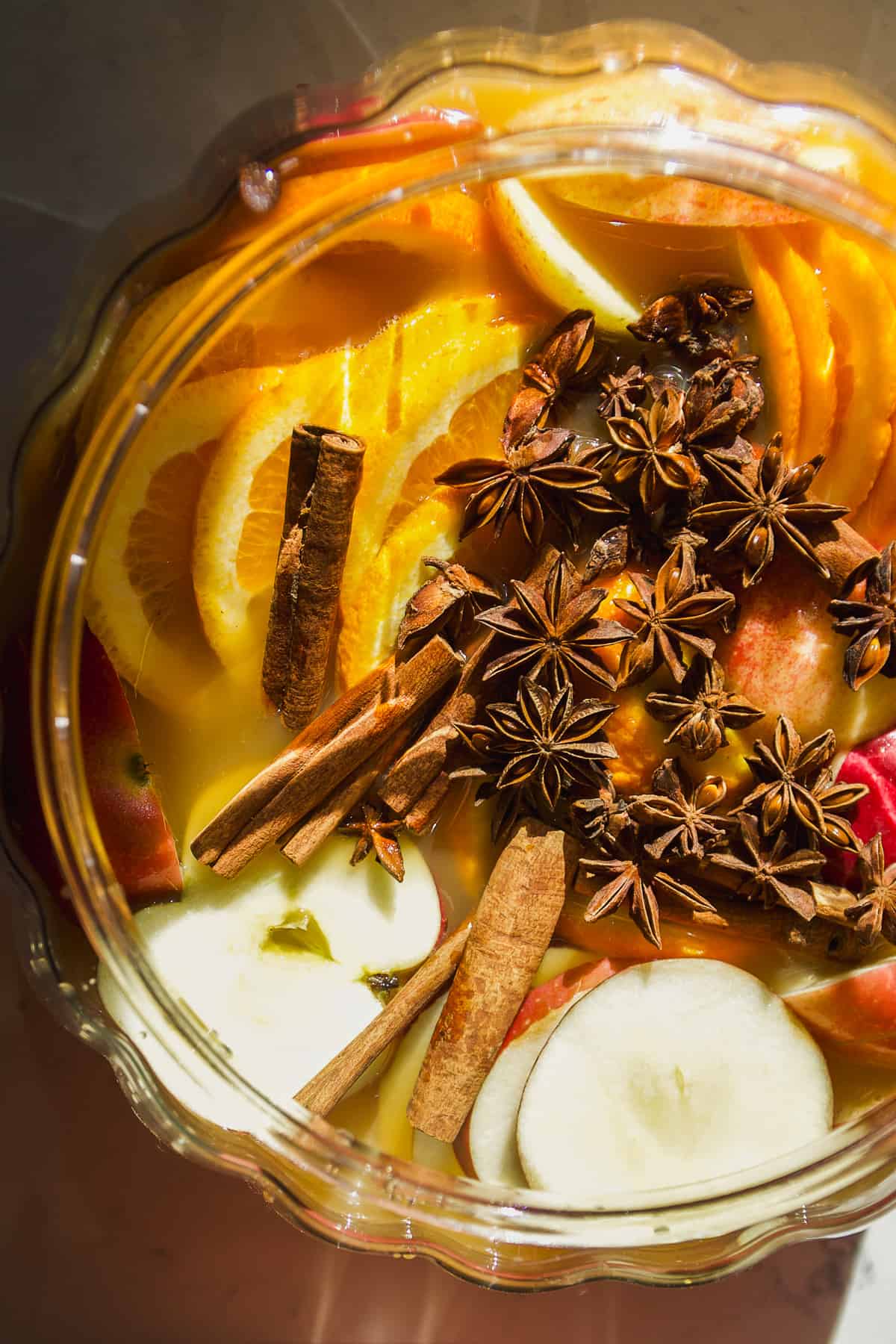 Overhead view of spiked apple cider punch with orange slices, apple slices, cinnamon sticks, and star anise.