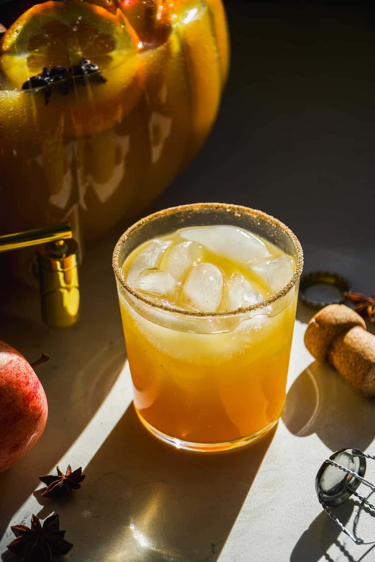 Apple cider spiked punch in a glass with the punch bowl behind.