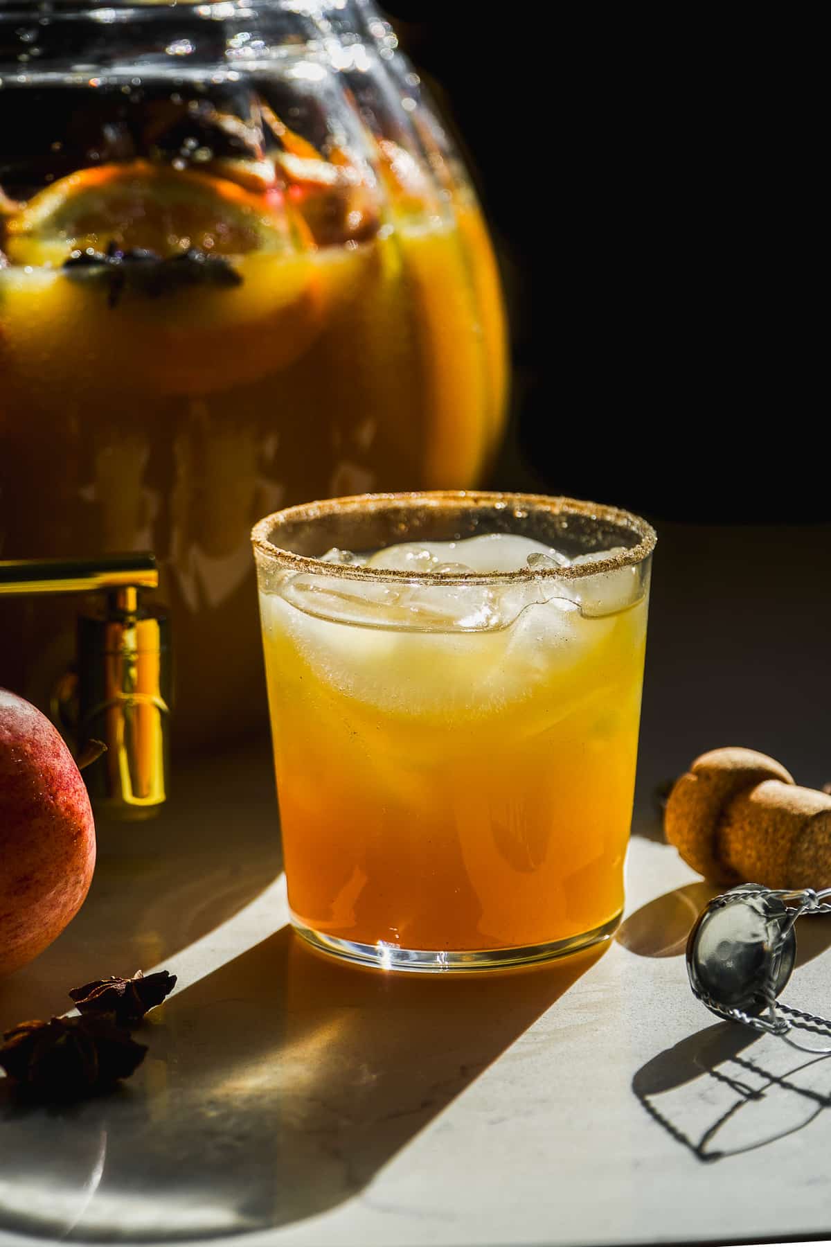 Spiked apple cider punch in a glass with the bowl behind.