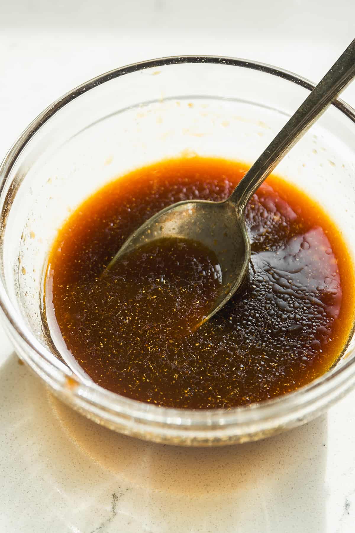 Teriyaki sauce mixed in a small glass bowl with a spoon.