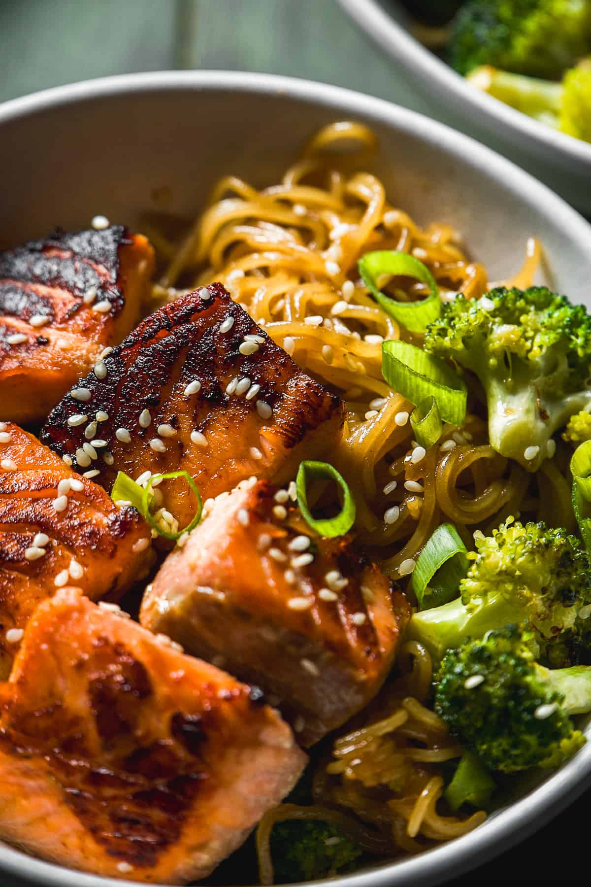 Up close view of a bowl of salmon teriyaki salmon noodles with sesame seeds on top.