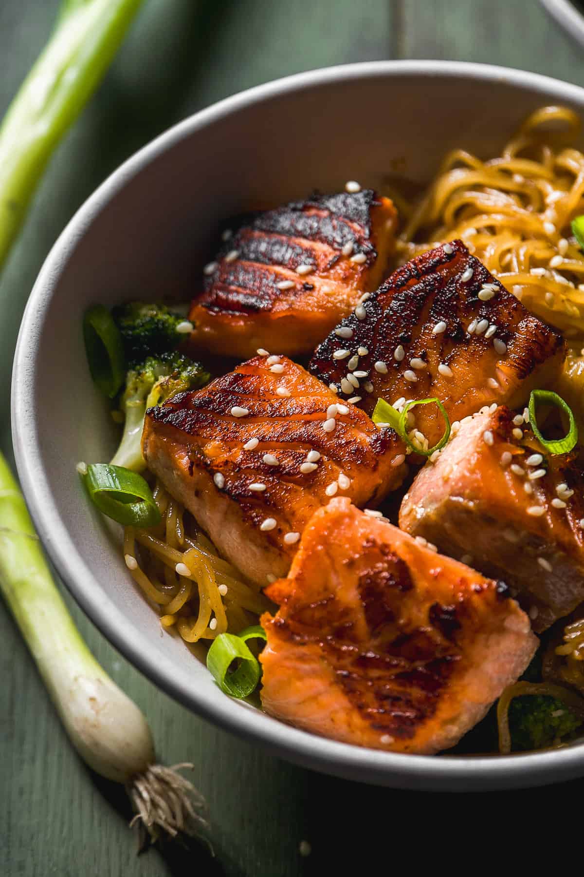 Teriyaki salmon on top of noodles with sesame seeds on top in a bowl.