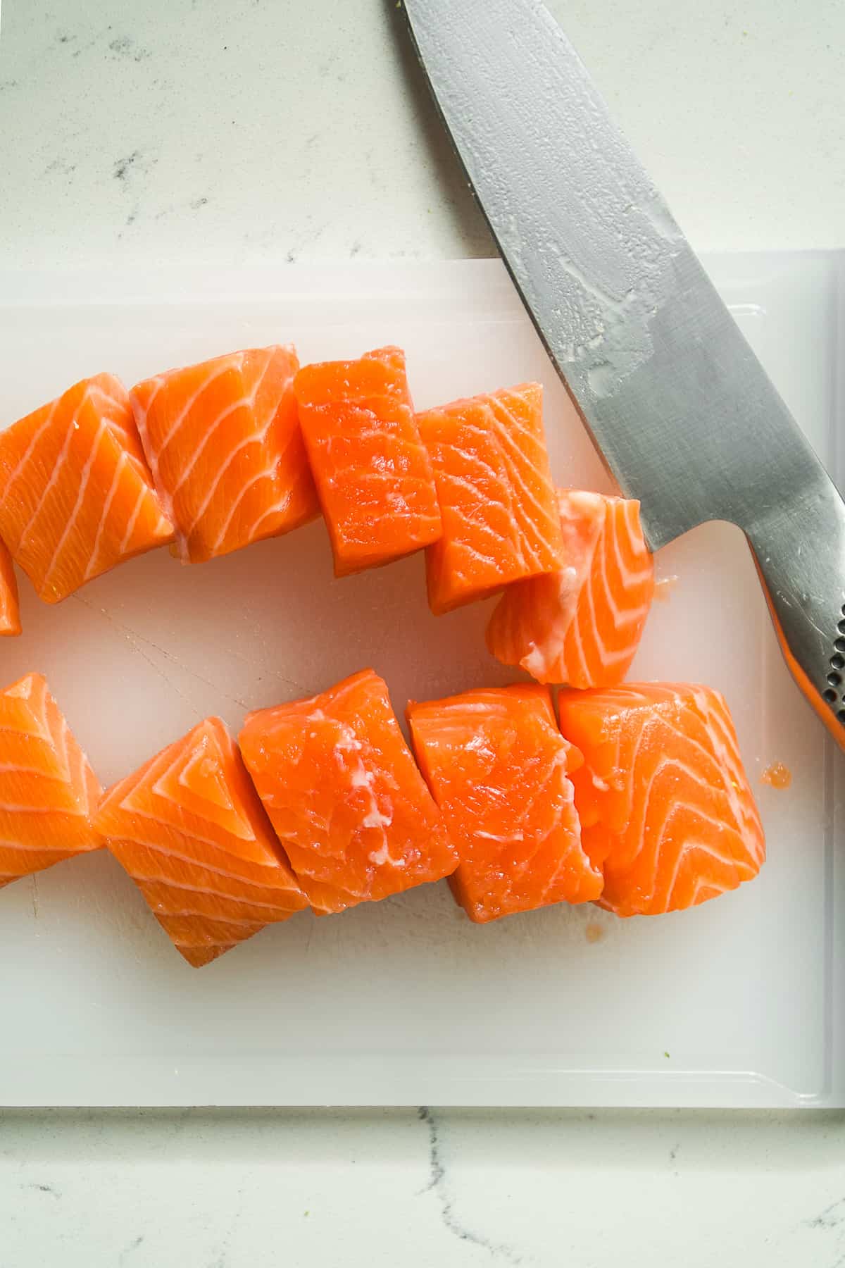 Salmon cut into cubes on a cutting board.