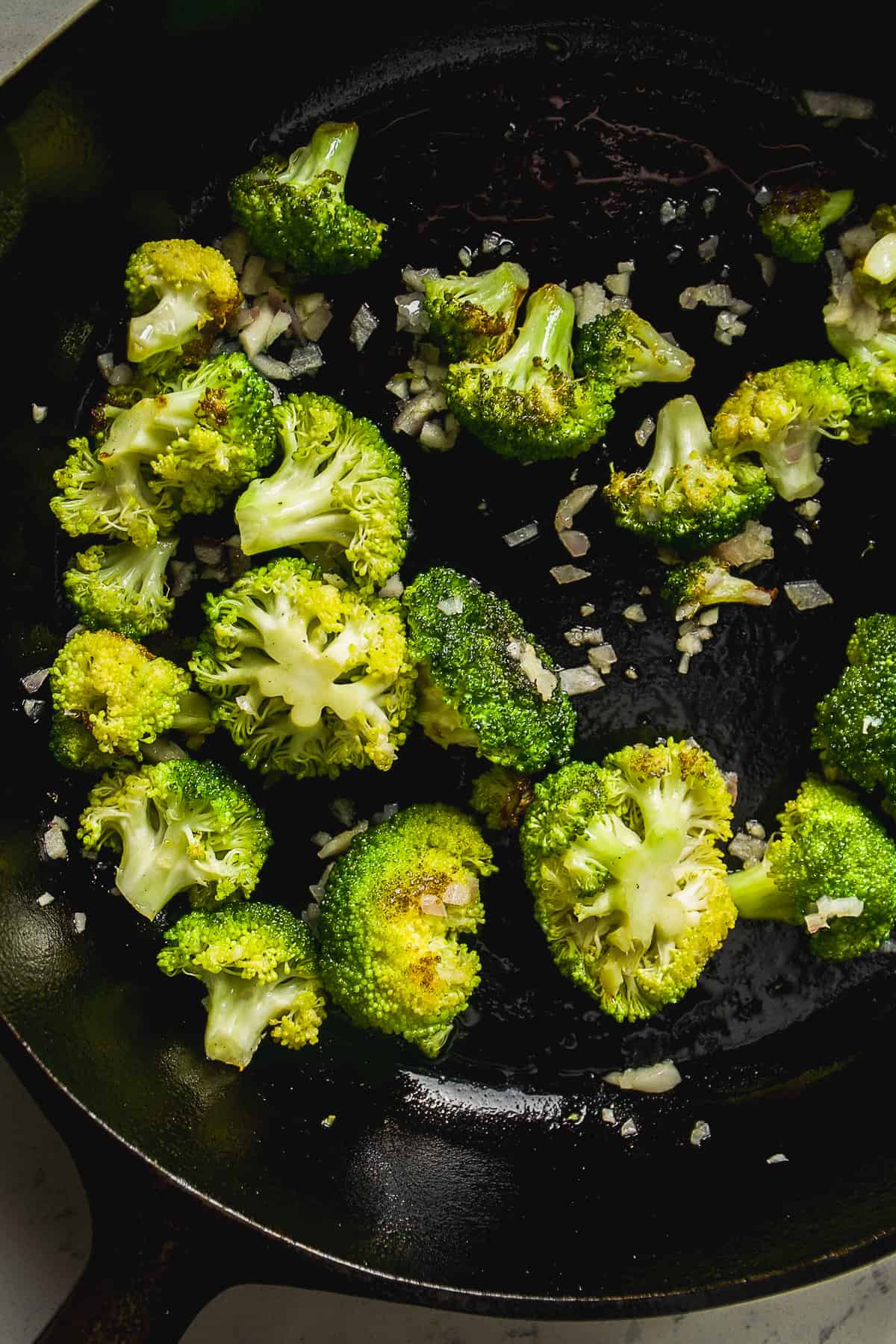 Broccoli cooking in a cast iron skillet.