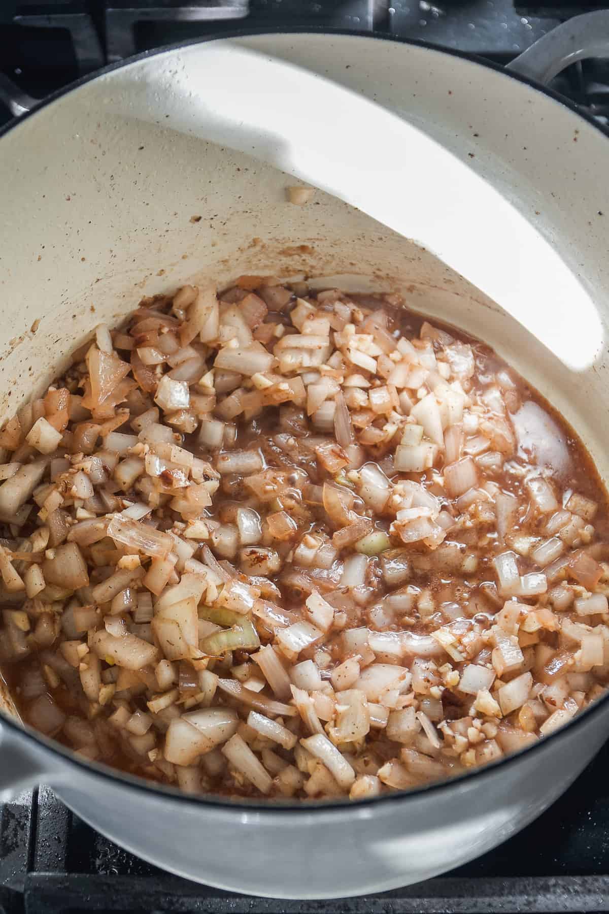 White onions cooking in a dutch oven with red wine.