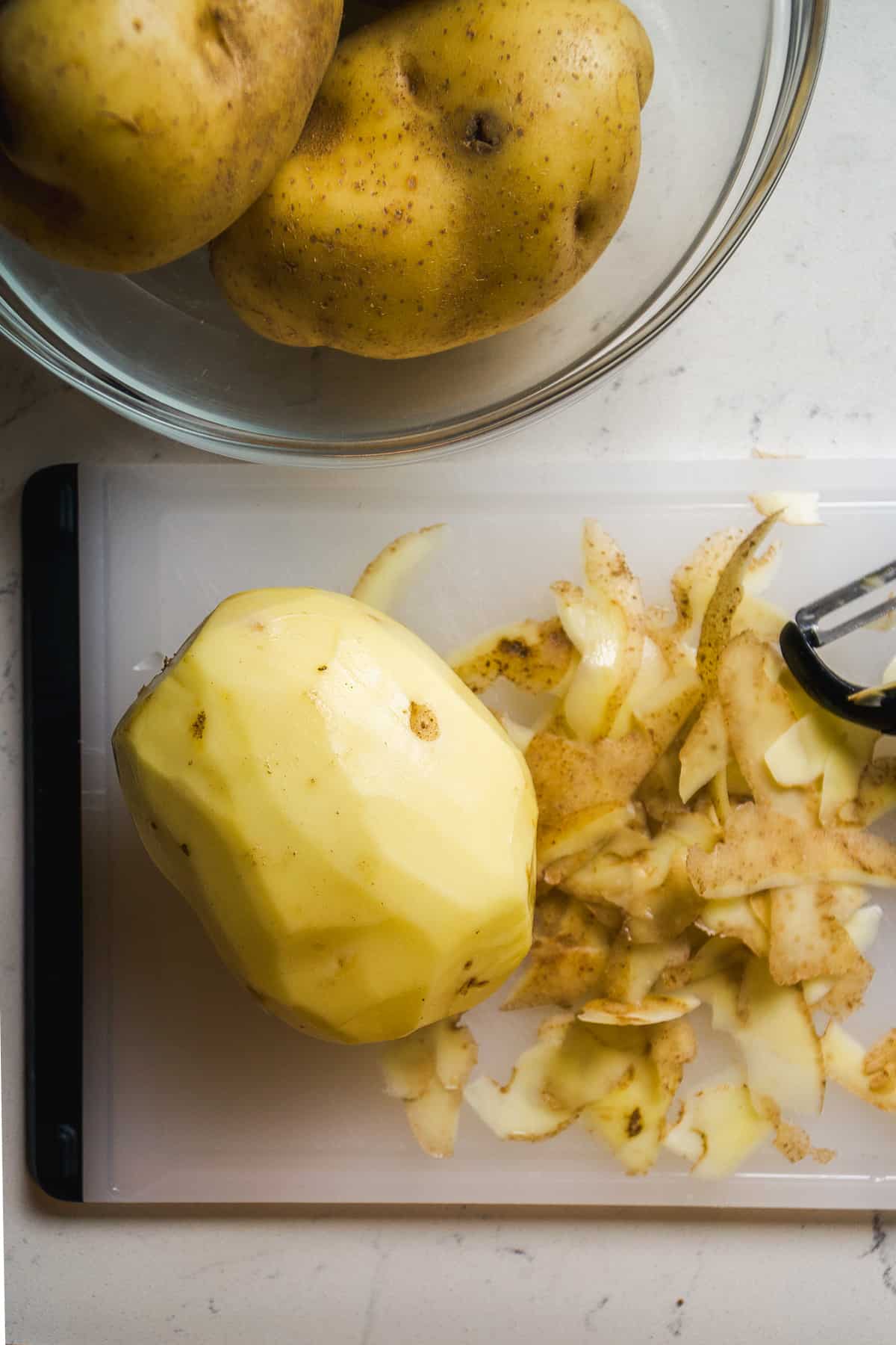 Potato skinned on a cutting board.