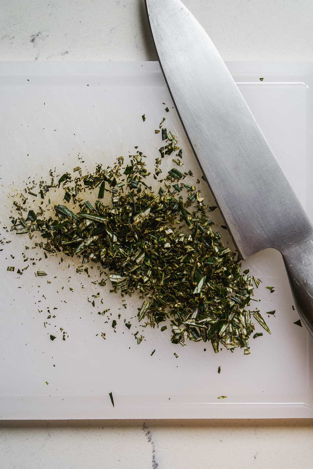 Rosemary cut into fine pieces on a cutting board.