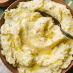 Overhead view of garlic mashed potatoes with rosemary and a large spoon.