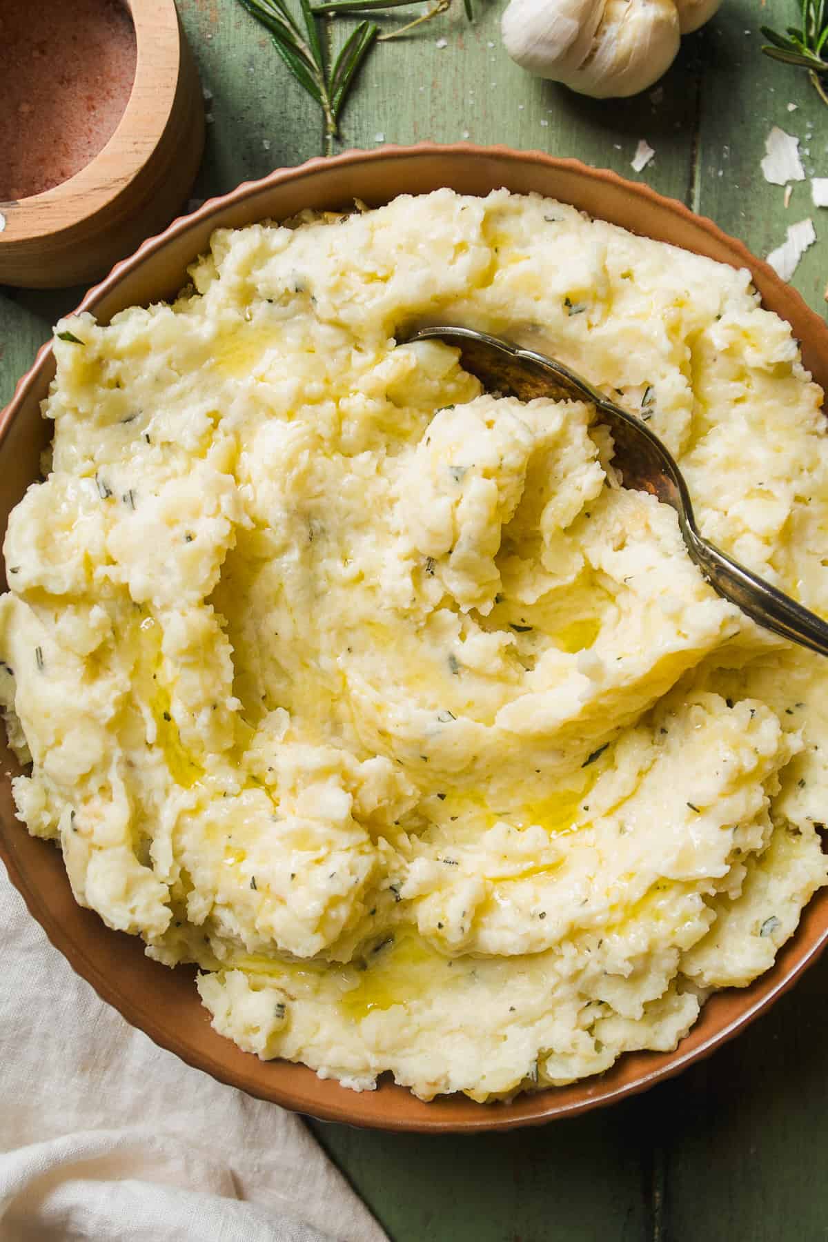 Overhead view of garlic mashed potatoes with rosemary and a large spoon.